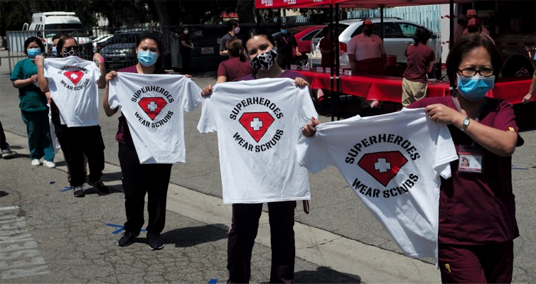 Nurses holding a Tshirt with Superheroes wear scrubs logo