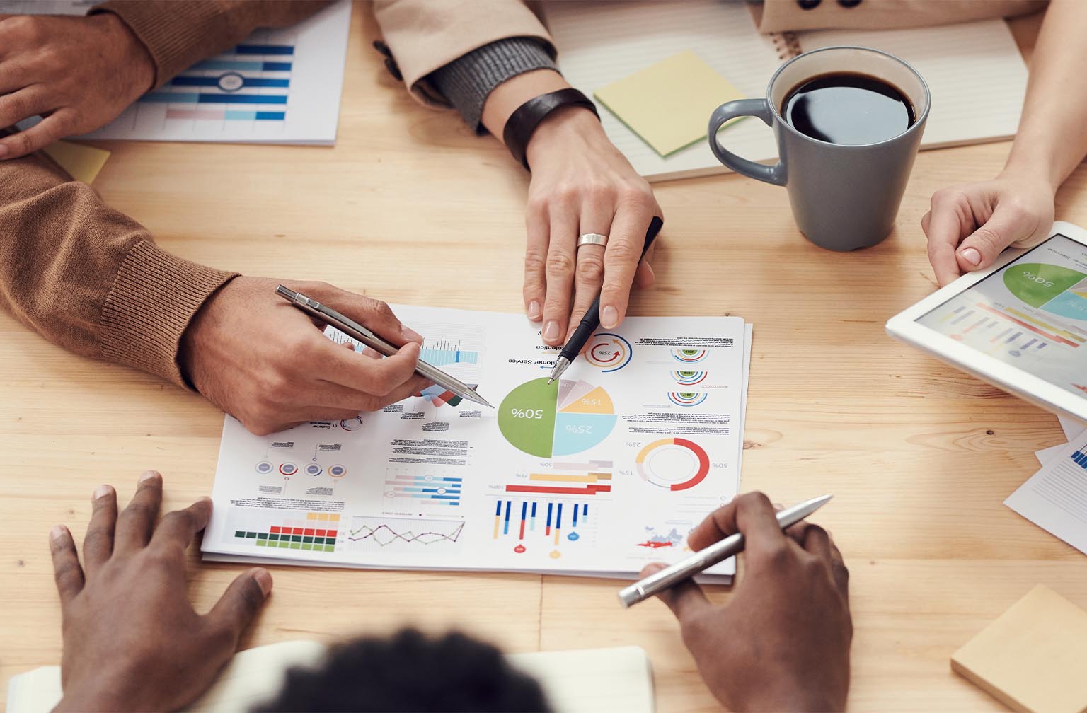 Office table with paper charts and businessmen's hands